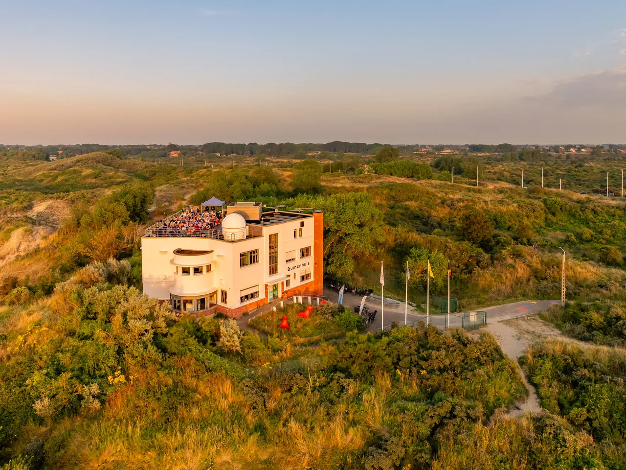 Het Duinenhuis van Koksijde te midden van de duinen bij zonsondergang.