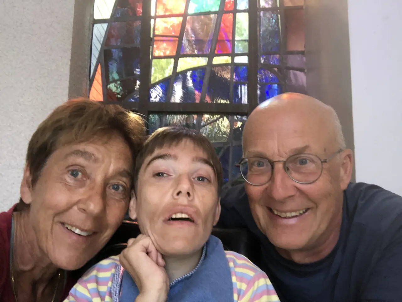 Frieda, Tine en Pol dicht bij elkaar voor een kleurrijk glasraam.