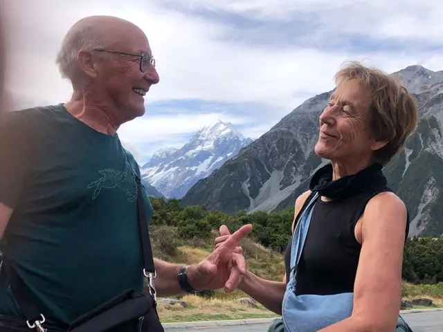 Pol en Frieda lachen naar elkaar, met de besneeuwde Mount Cook op de achtergrond.